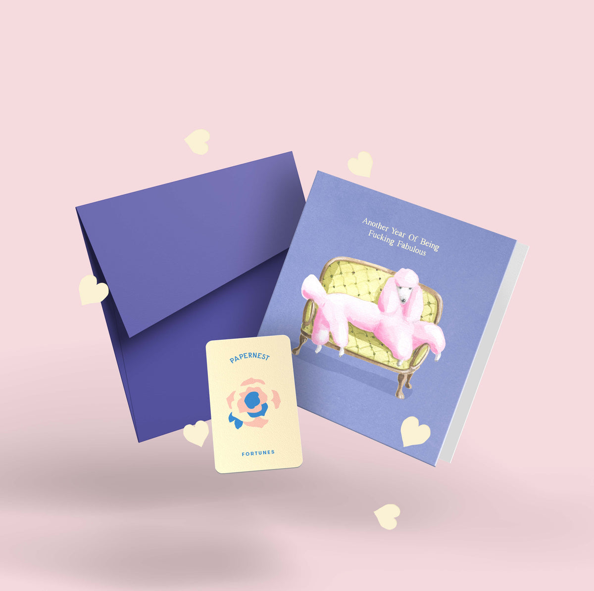 Funny birthday card with watercolour pink poodle on chaise, purple envelope, Papernest novelty fortune card, and plantable seed paper confetti hearts on pink background