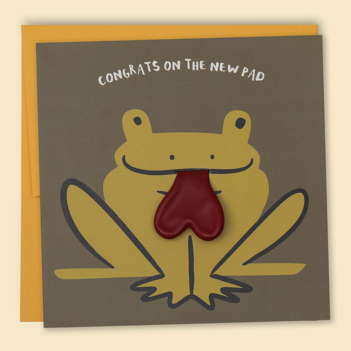 A greeting card with a cartoon frog design, with the text 'CONGRATS ON THE NEW PAD' across the top. The frog has a red heart balloon for a tongue  — Australian-made greeting card by Papernest